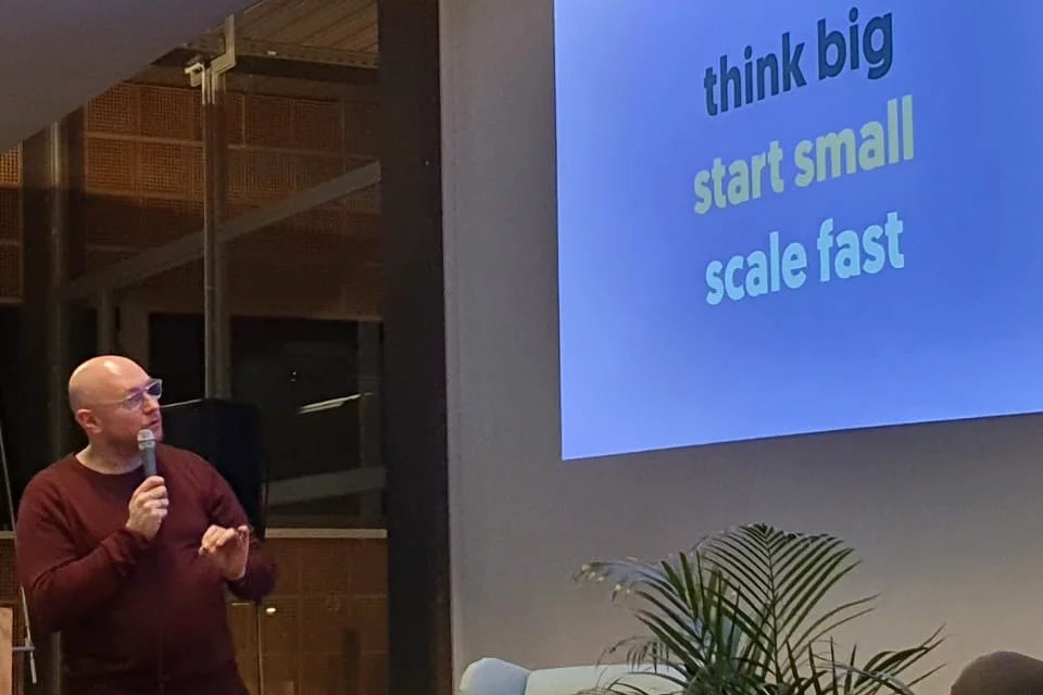 Tobias Treppmann spricht mit Mikrofon vor einer Folie mit dem Satz „think big, start small, scale fast“